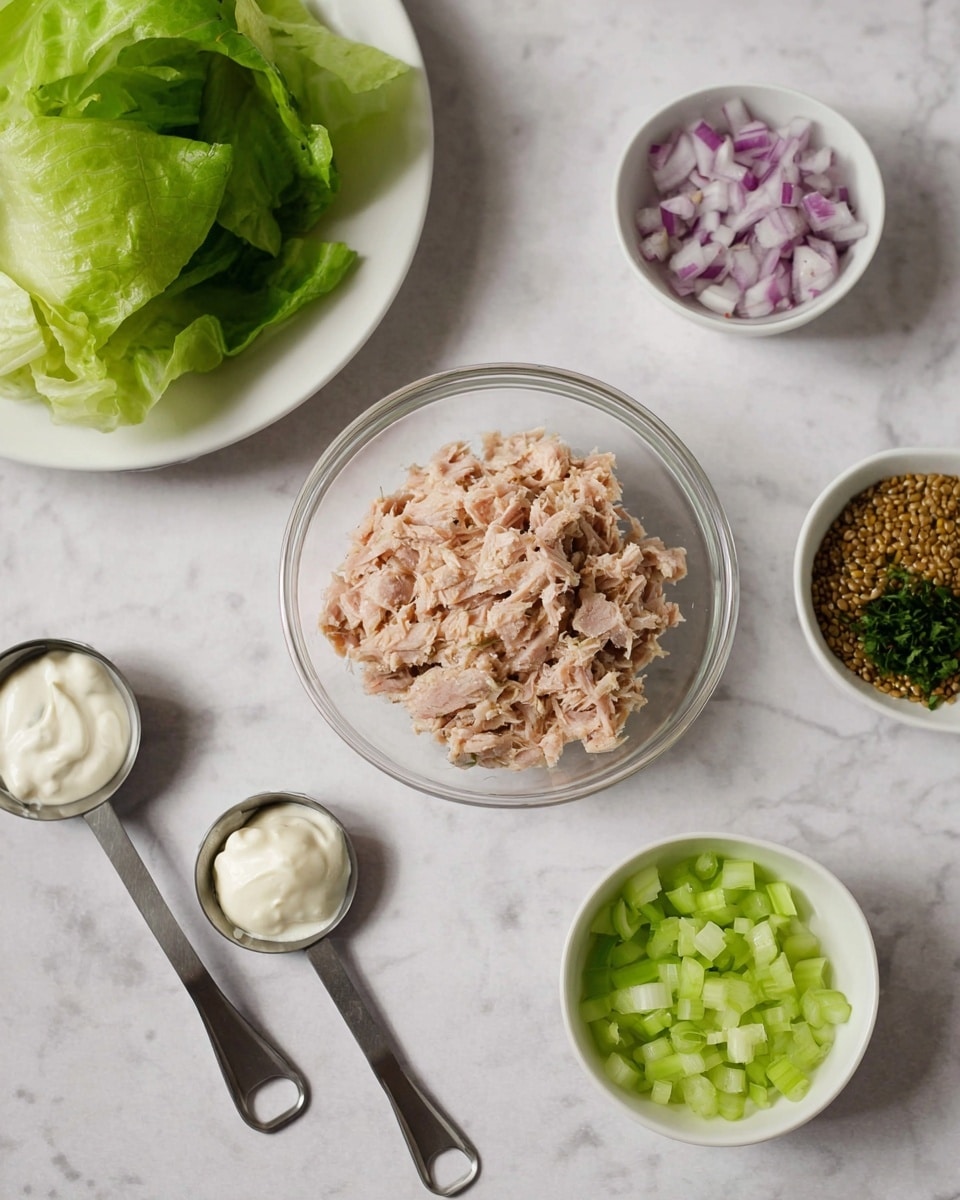 The image shows a collection of small white bowls and measuring cups arranged on a white marbled surface. In the center, there is a clear glass bowl filled with light pink shredded tuna. To the top left is a white plate holding fresh, light green leafy lettuce. To the top right, there is a white bowl containing finely chopped purple onions. Below the bowl of tuna, there is a white bowl with finely chopped pale green celery. On the left side, three metal measuring spoons are placed with different ingredients: one holds white creamy mayonnaise, another holds green chopped herbs, and the last one contains whole grain mustard seeds in a brownish sauce. The scene looks like fresh ingredients ready to be mixed, photo taken with an iphone --ar 4:5 --v 7